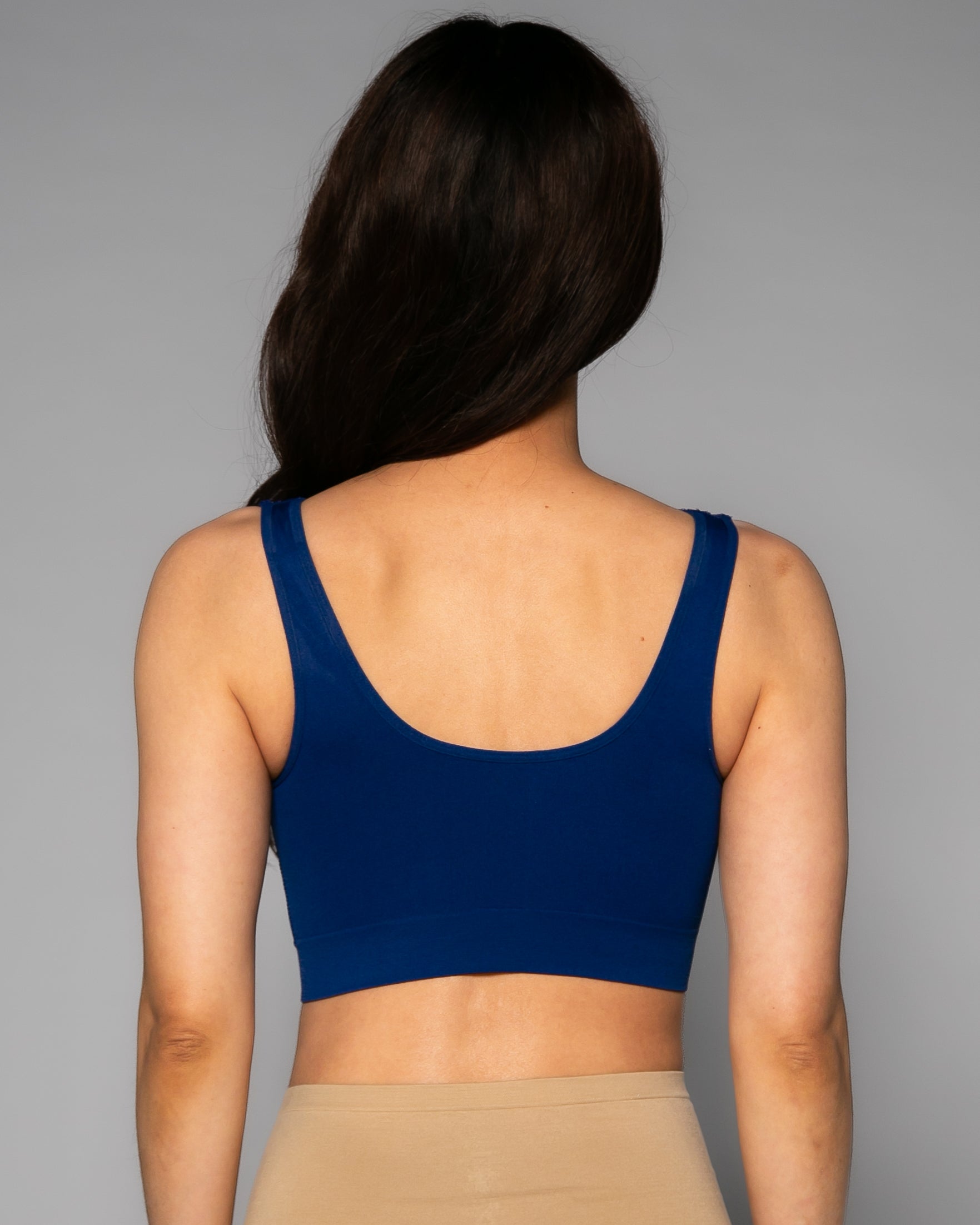 Person wearing a blue sports bra and beige leggings against a gray background